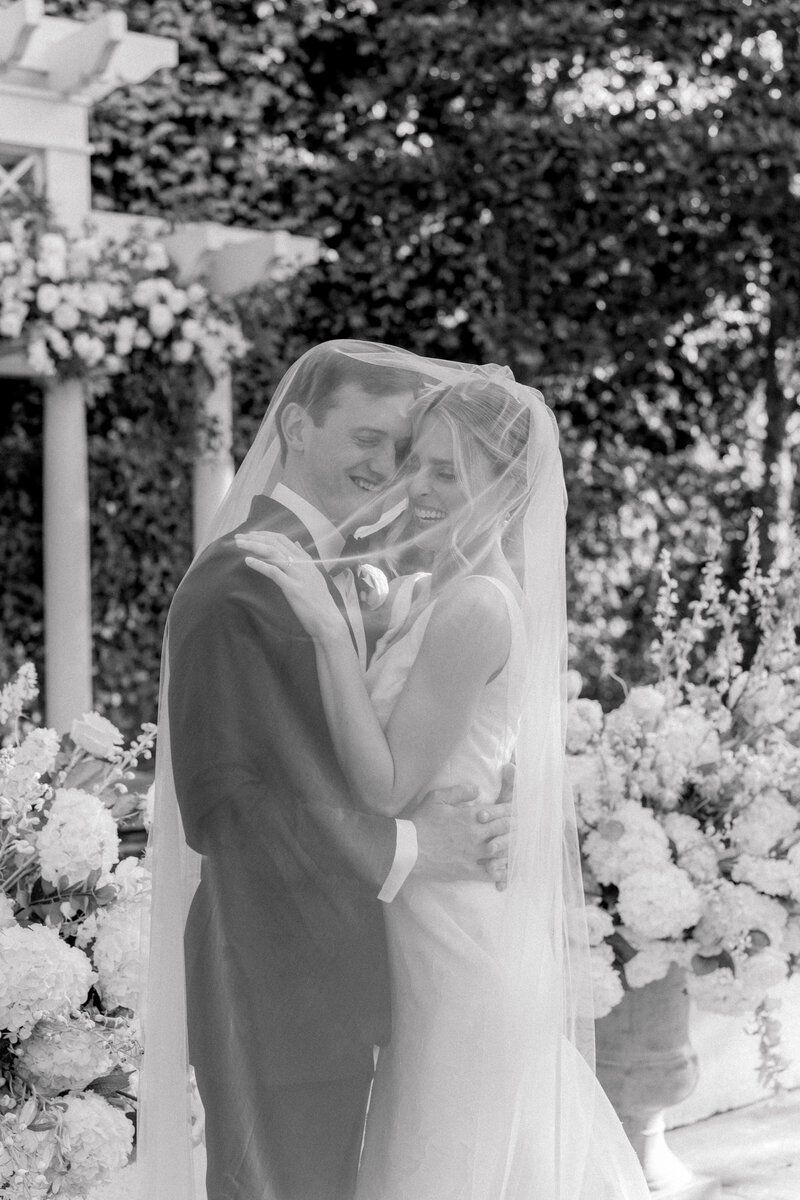 Black and white photo of bride and groom laughing under veil.  Photographer Charleston.