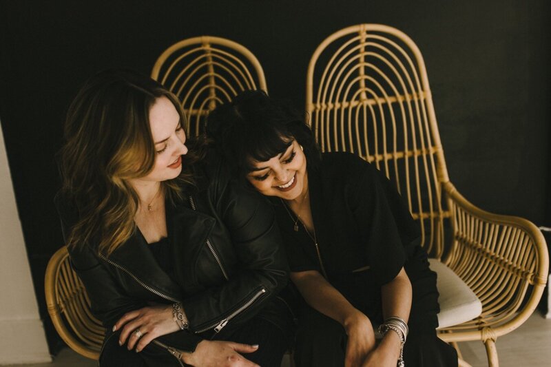 two women sitting on a bench together and laughing