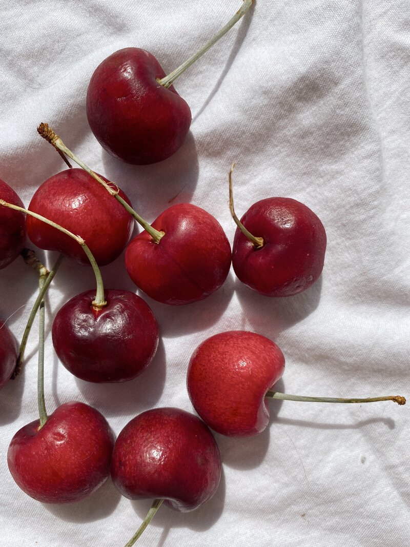 Red cherries laying on white fabric