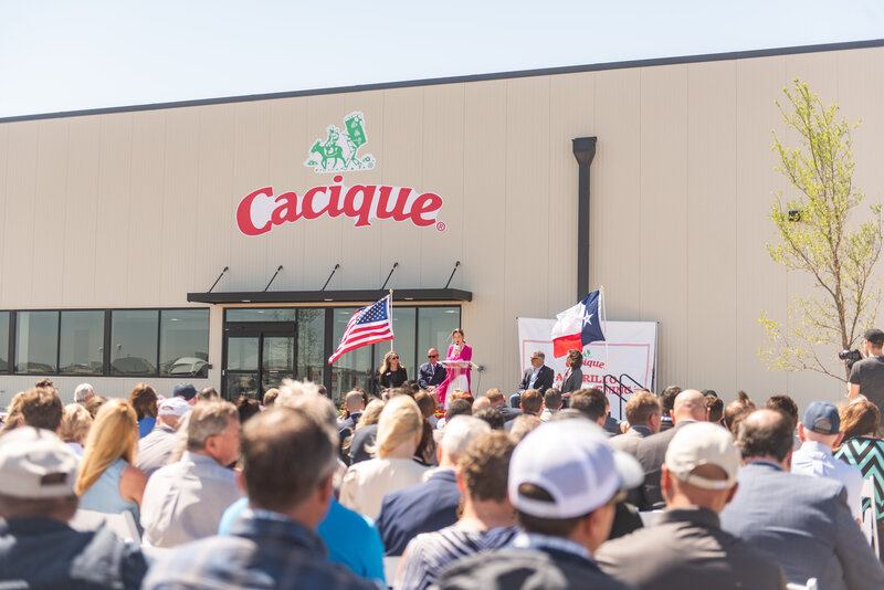 A crowd frames the speakers in front of an industrial factory grand opening ribbon cutting ceremony event