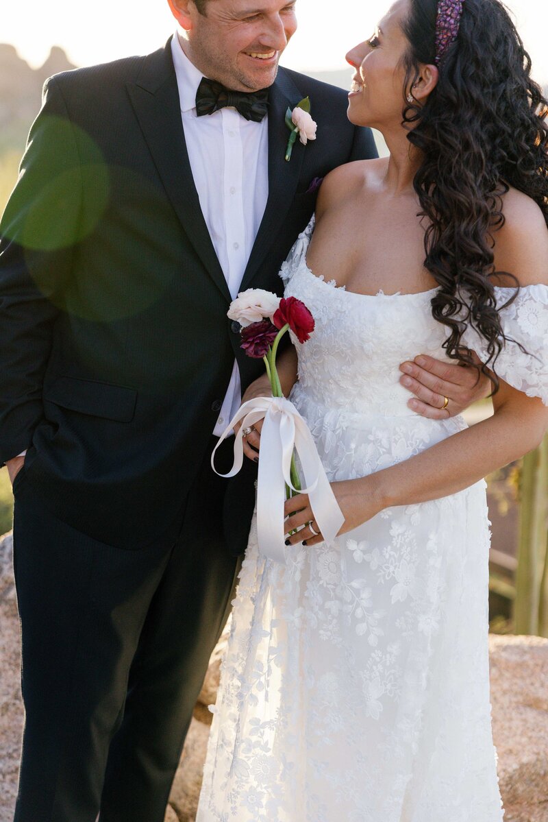 Bride and groom cuddle and smile at each other.