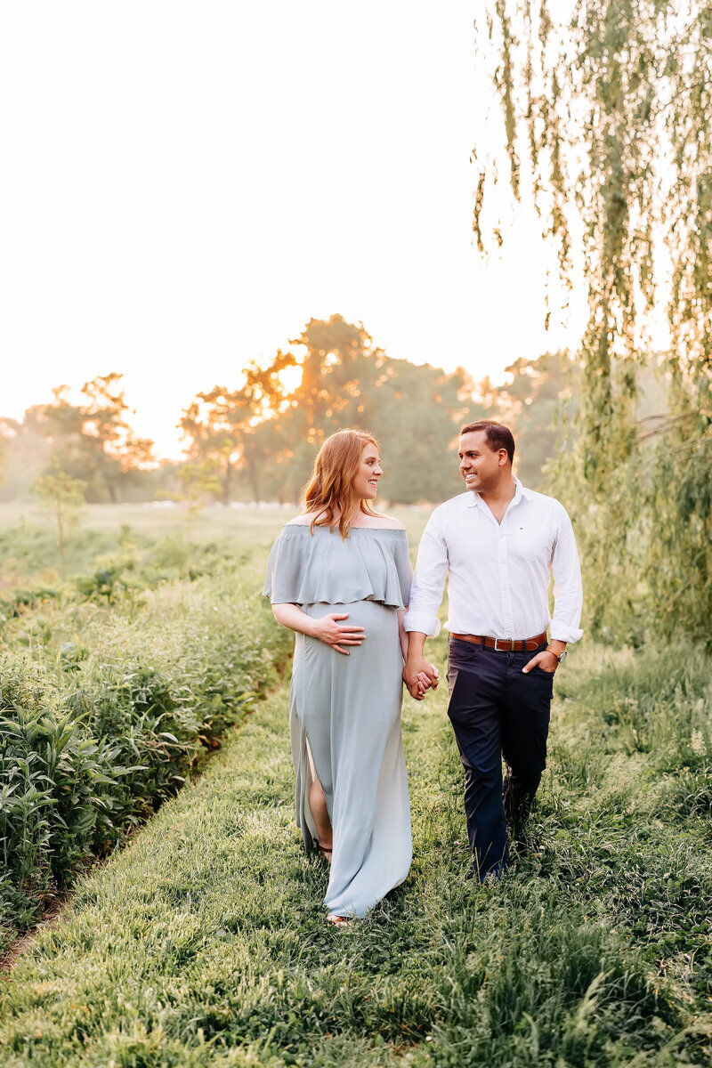 parents holding hands and walking through forest park at maternity session