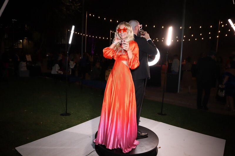 Guests posing with drinks on a 360 video platform surrounded by ring lights and string lights at an outdoor corporate event, captured by MISGIF’s immersive 360 photo booth in Phoenix, Arizona