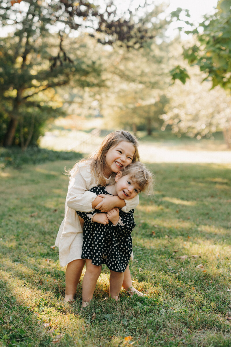 Two young girls embracing each other during fall mini session in St. Louis, Missouri