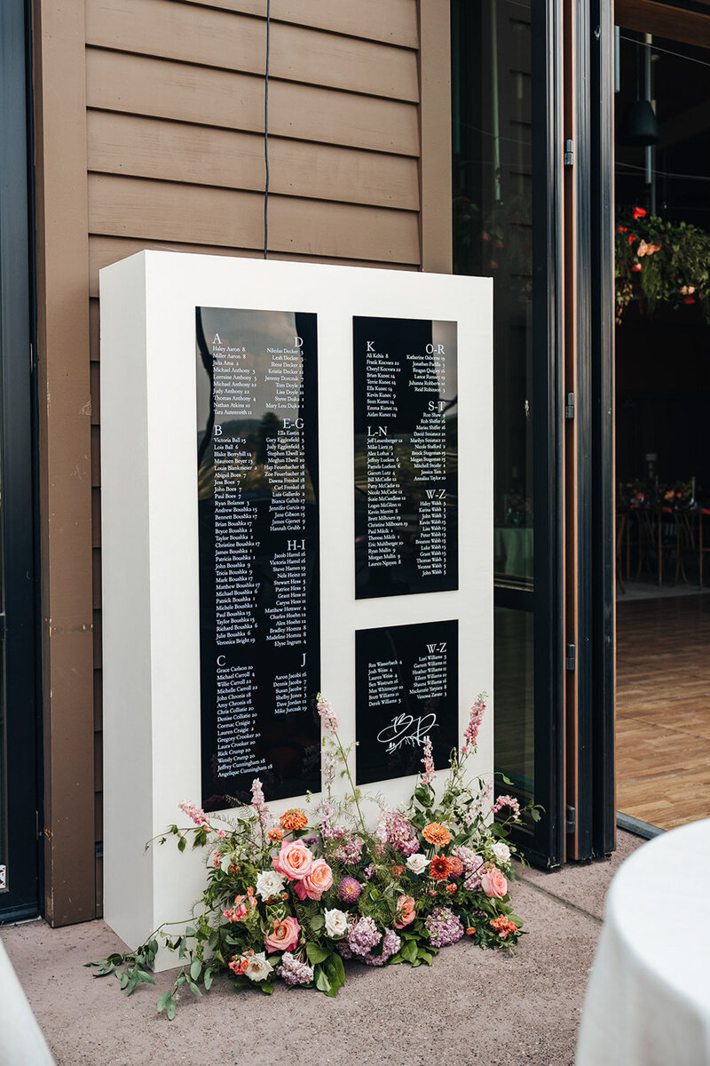 Custom wedding seating chart with flowers sitting at its base, representing full service design and calligraphy by Life in Letters.