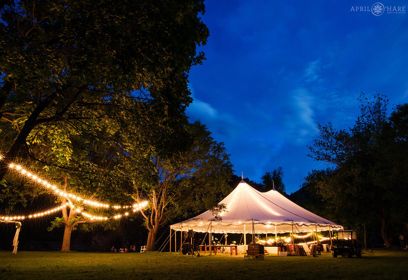 Nice large white sailcloth tent at Riverbend wedding reception lit up at dusk in Lyons CO