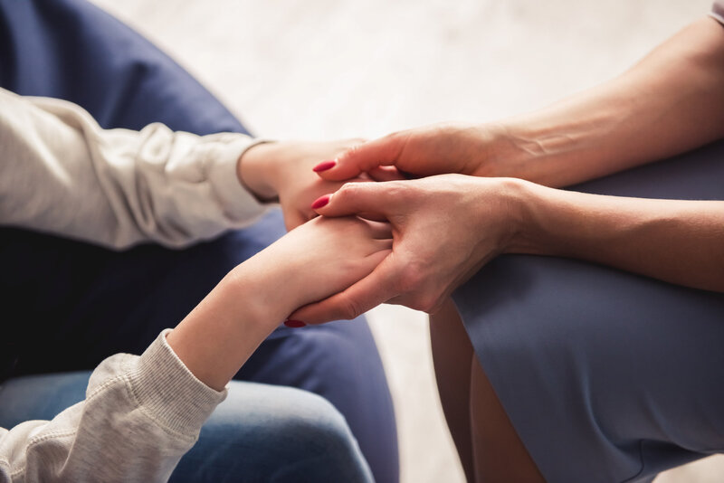 Les mains d'une femme adulte prenant celle d'un enfant