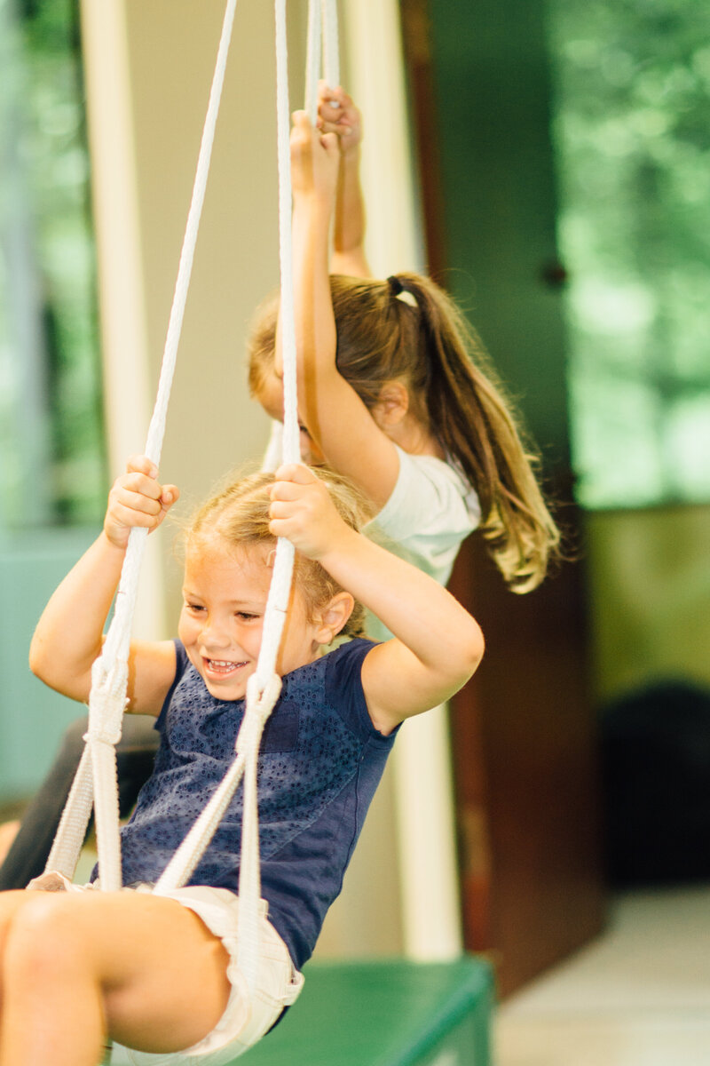 two young girls swinging together in a therapy swing at a pediatric occupational therapy clinci