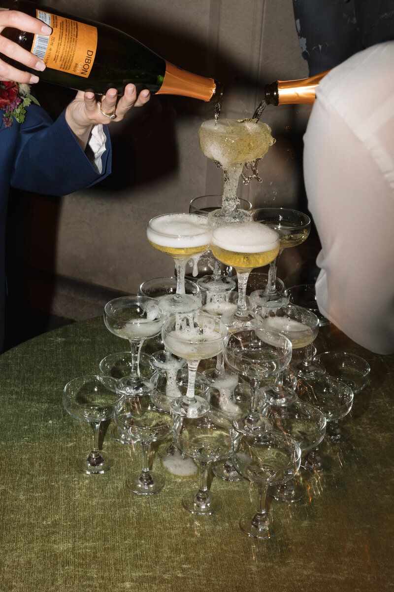 Champagne tower photos of a bride and groom during their wedding reception