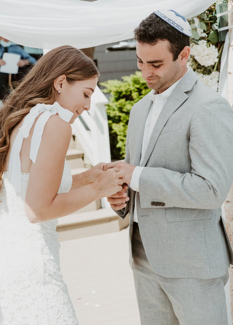 Bride putting ring on groom at Los Angeles wedding ceremony