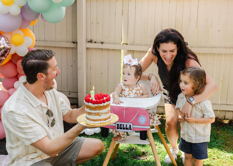 Family presenting baby with a cake at a first birthday party in NJ