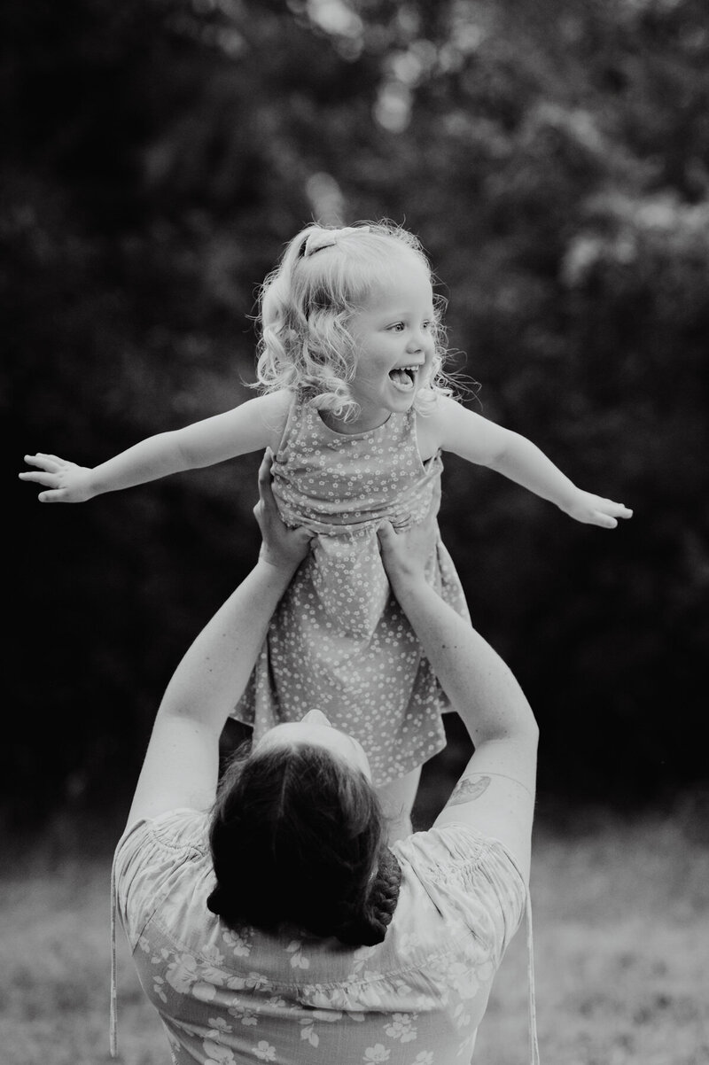 Little girl laughing as she is being lifted into the air by her mum