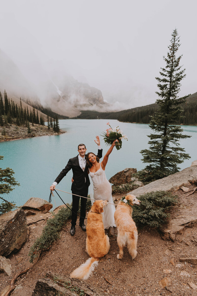 Bride and groom embracing at golden hour in Banff, surrounded by forest and mountain rock, with a warm-toned bouquet and soft sunset lighting.