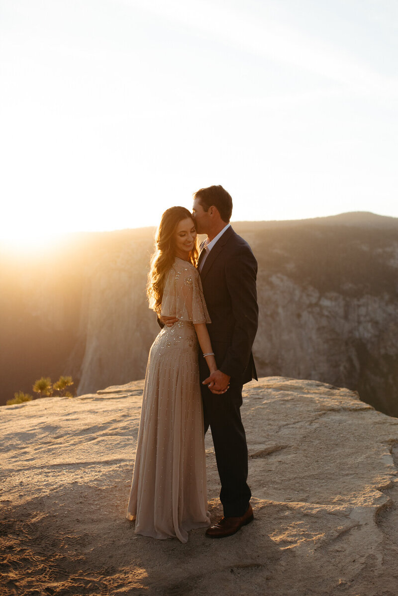 Yosemite elopement at taft point, bride and groom are holding hands and smiling with sun rays behind them
