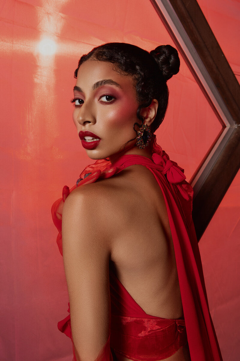 Stylish portrait of Nic Shiya in a vibrant red outfit with sleek hair, captured by Ylva Erevall against a red background.