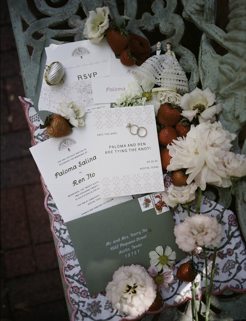 Garden party outdoor wedding stationery suite with custom illustrations on wedding invitation, envelope liner, details card, and save the date pictured with strawberries and a vintage wedding cake topper with Good Seed Floral flowers and photographed by Taylor Friedman Photo