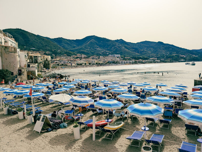 Sunny day on the beach with umbrellas in the sand and water on the horizon