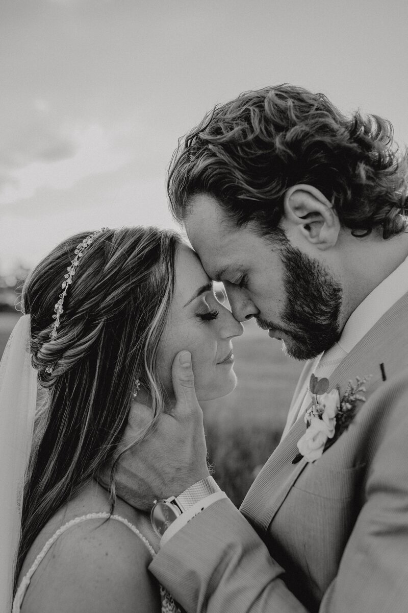Black and white photo of bride and groom leaning forehead to forehead