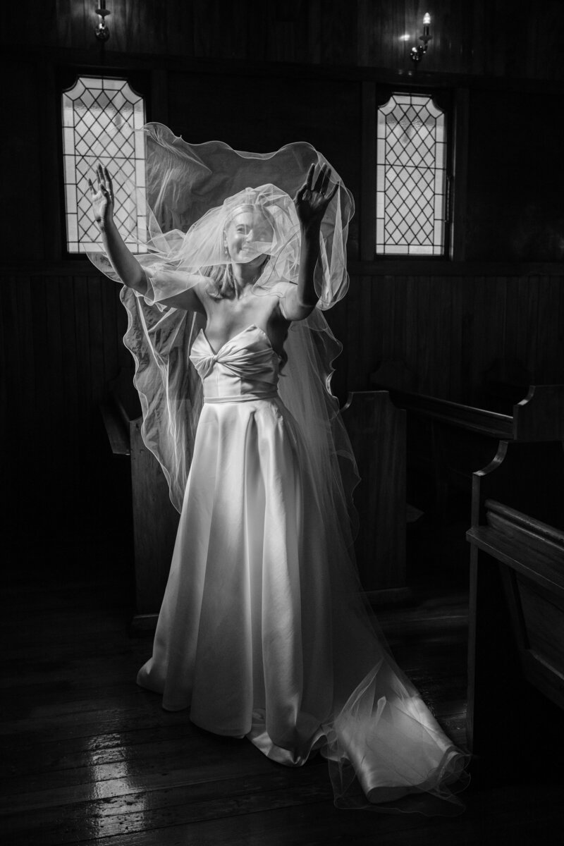 dramatic black and white photo of bride inside old church at waimumu farm chapel wedding venue