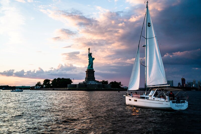 Sailboat floating in the water with the Statue of Liberty in the background