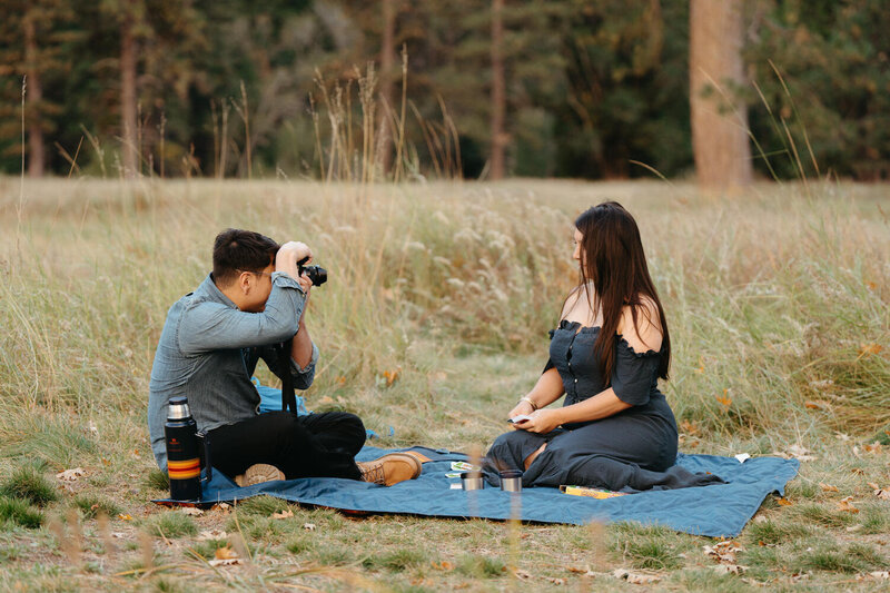 Artistic Elopement Ideas | Couple having a picnic and groom is taking a photo of the bride 