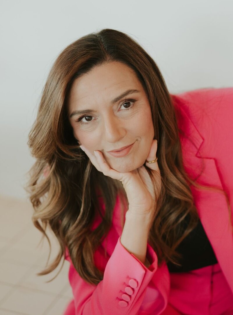 Idit Sharoni, LMFT, founder of Relationship Experts, smiling warmly in a pink suit, representing her compassionate and expert approach to helping couples improve their communication and intimacy, and heal and reconnect after infidelity.