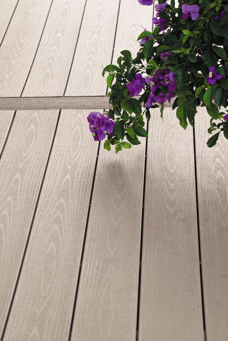 Composite decking with purple flowers hanging over it. 