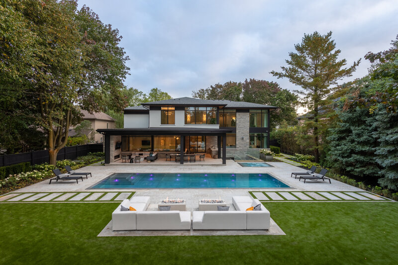 wide shot of a back of a family house with a rectangular pool and a lounge