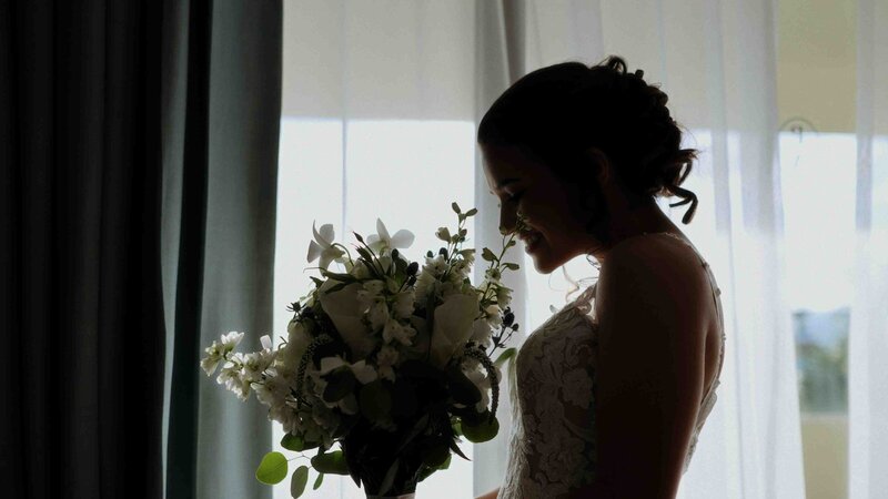 Bride smiling as she admires her vibrant tropical bouquet.
