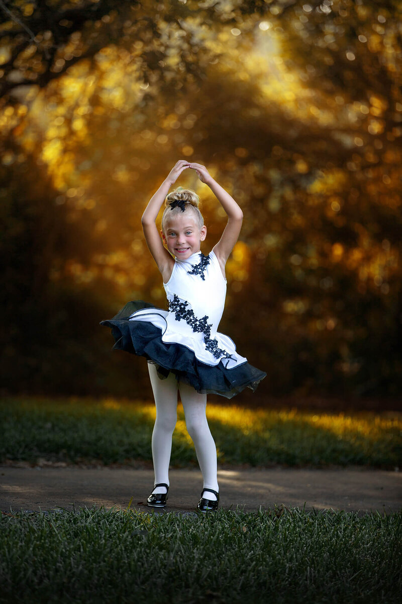 adorable little girl posing in her dance attire with beautiful golden light in the background