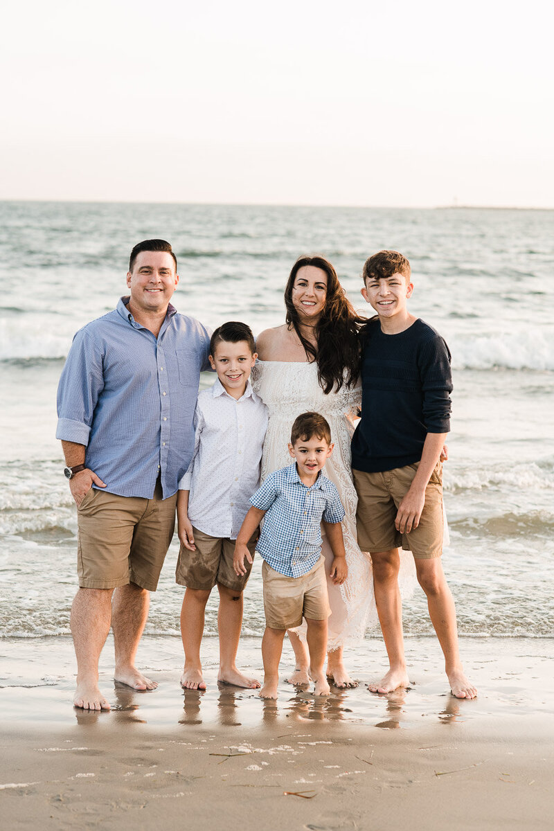 family on beach in front of ocean barefoot
