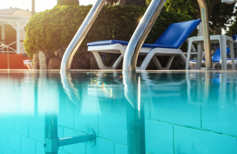 pool ladder in pool water with pool chair in the background