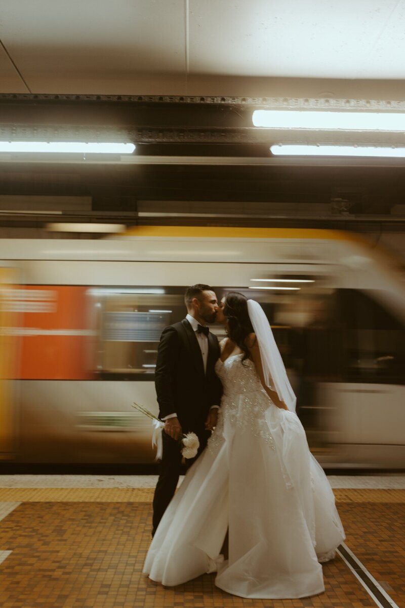 Image of couple in front of a moving train in the subway train station