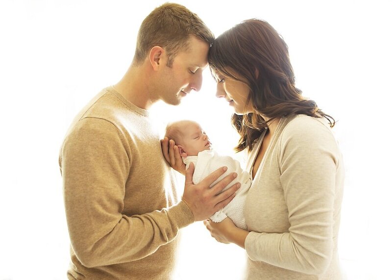 Parents smile over their baby during their newborn session