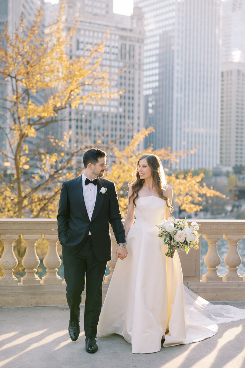 A bride and groom share a moment in a lush garden with skyscrapers in the background during their Four Seasons Chicago wedding, coordinated by Chicago wedding planner Savoir Fête