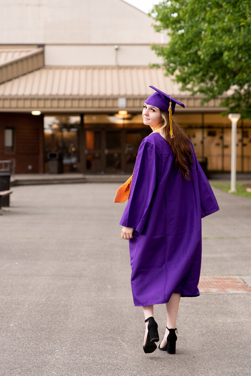 Graduate from Sumner High School wearing her purple cap and gown on the school's campus for senior portraits with Western Sky Photography
