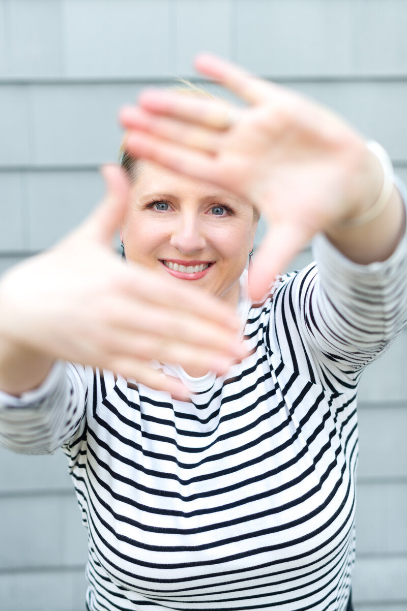 Fun branding photography image of Kristin Palkoner holding hands up in front of her face to frame a still image.