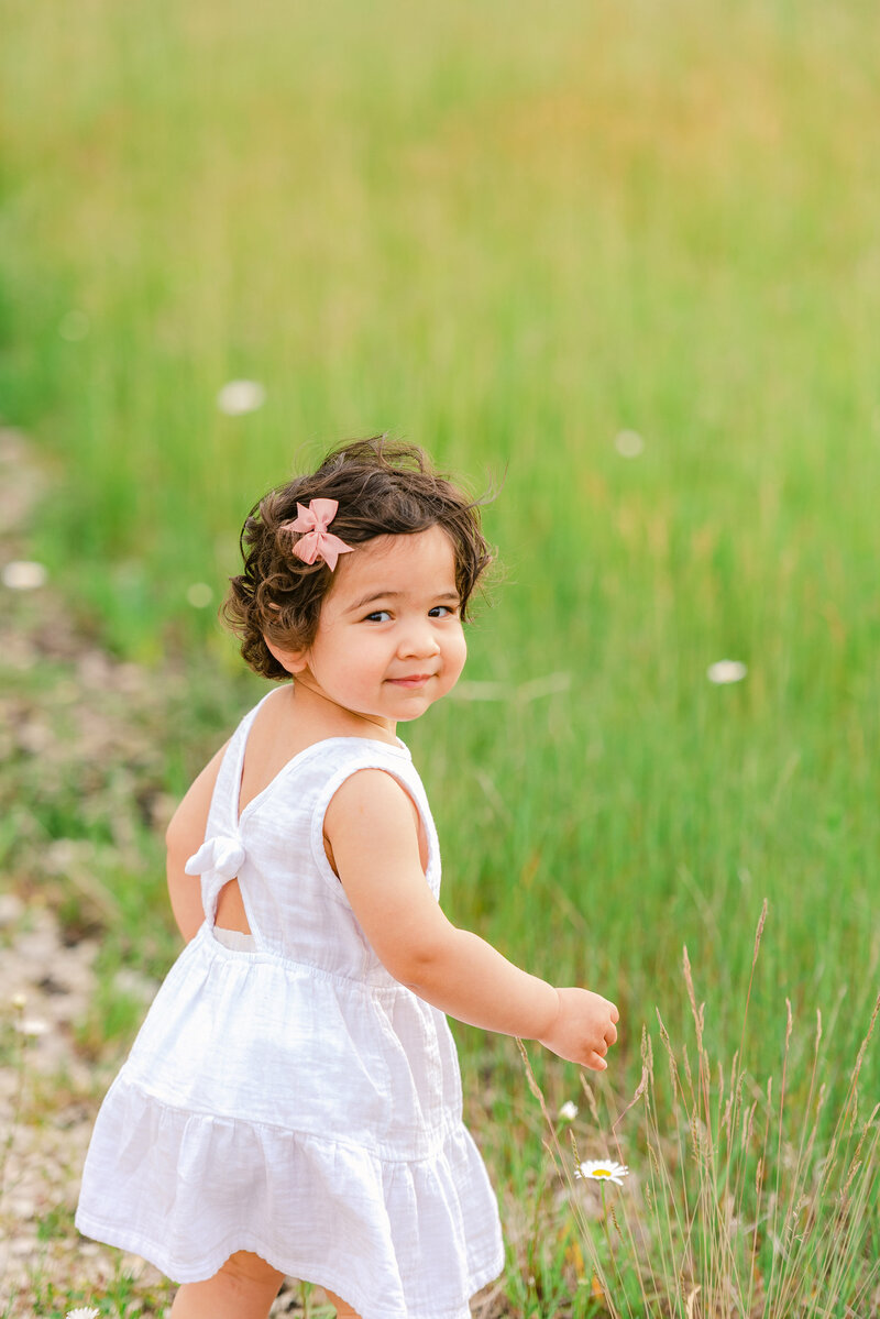 Little girl with white dress standing in a meadow
