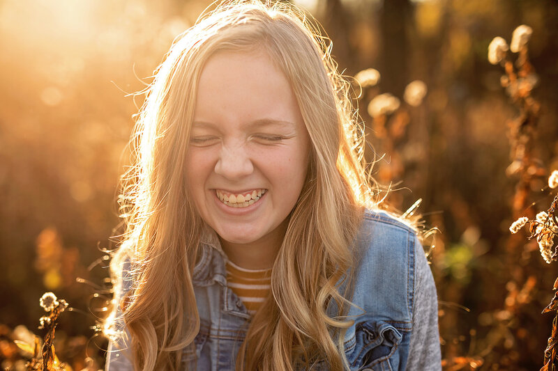 Young girl laughing with eyes closed in sun soaked image