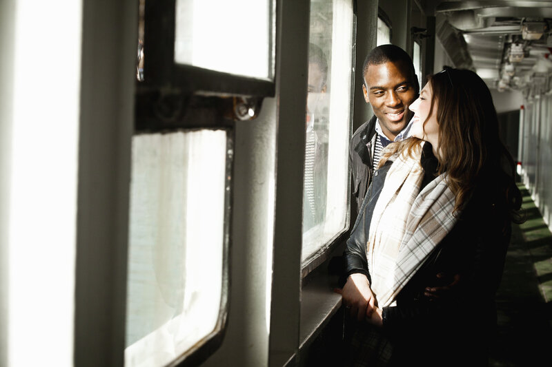 Interracial couple smiling and embracing near a light filled window – representing interracial couple counselling support with Freedom Couple Counselling in Melbourne.