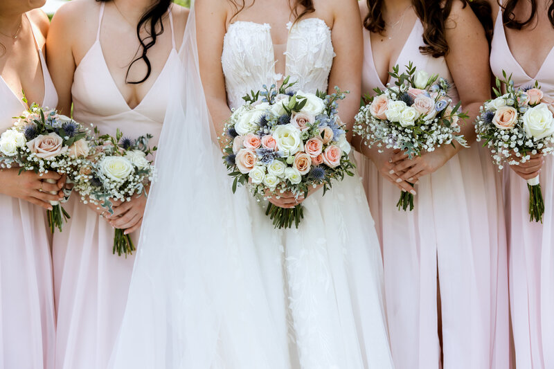 Minnesota bride posing with her bridesmaids during her springtime wedding holding bouquets of bright spring flowers