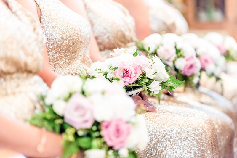 Detail shot of bridal bouquets resting uniformly in bridesmaids laps during the ceremony