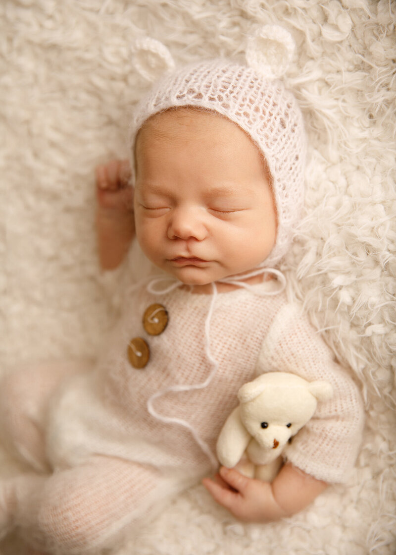 Newborn in knit bear romper and hat