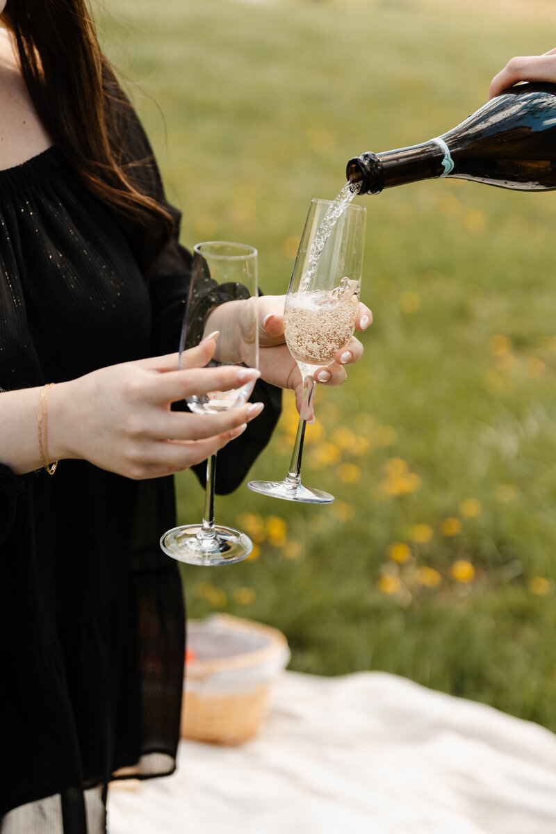 Engaged couple celebrating with a champagne pop during their Kentucky engagement session, laughing and full of joy.
