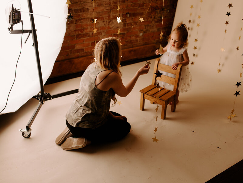 woman playing with girl in photography studio