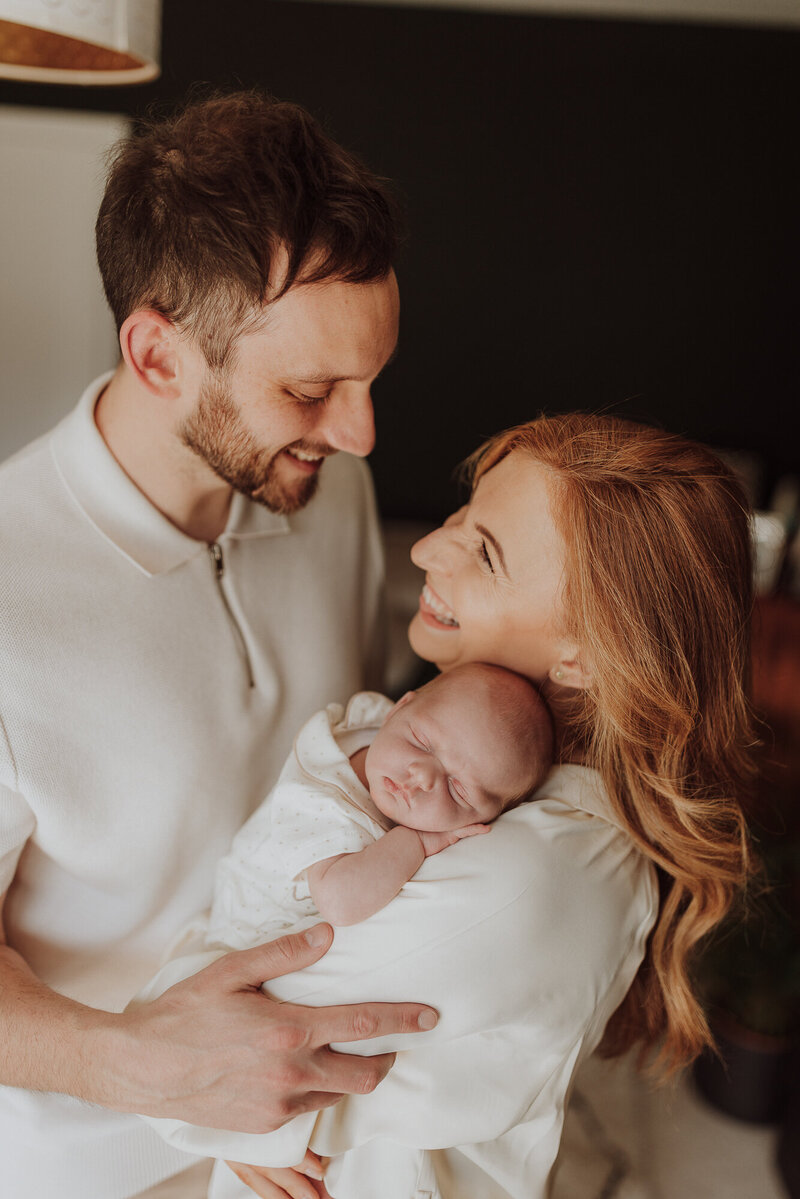 Parent smiling with newborn baby during photoshoot