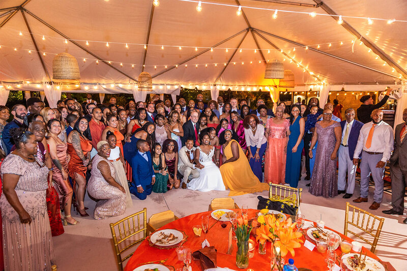 A large wedding group photo taken at the end of the night under string lights, captured as part of a no-first-look wedding day photography timeline.