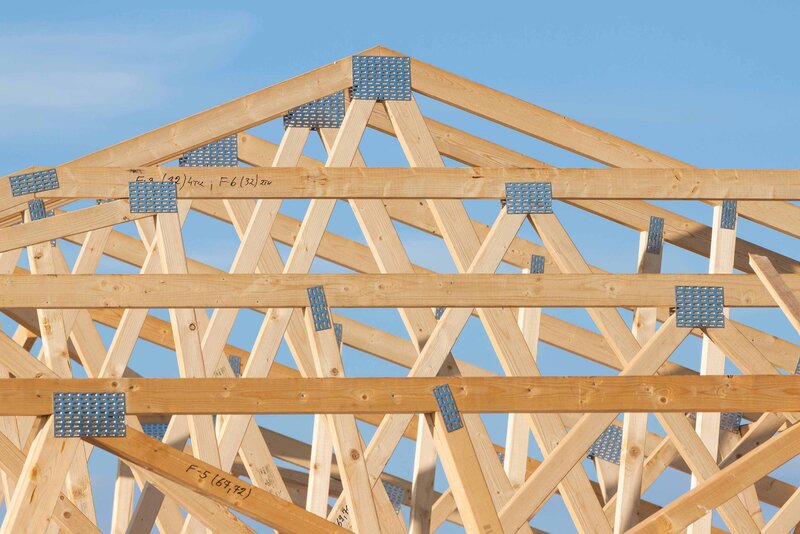 Wood trusses on roof against blue sky