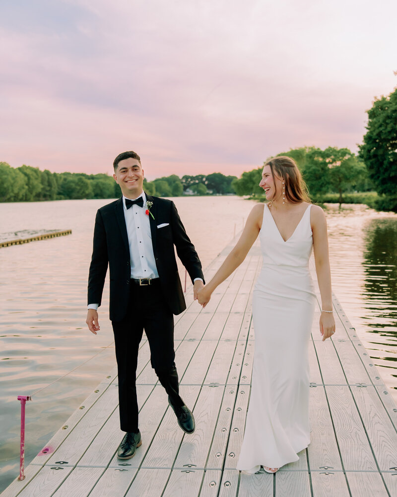 Newlyweds hold hands while walking on a pier at Camden County Boathouse.