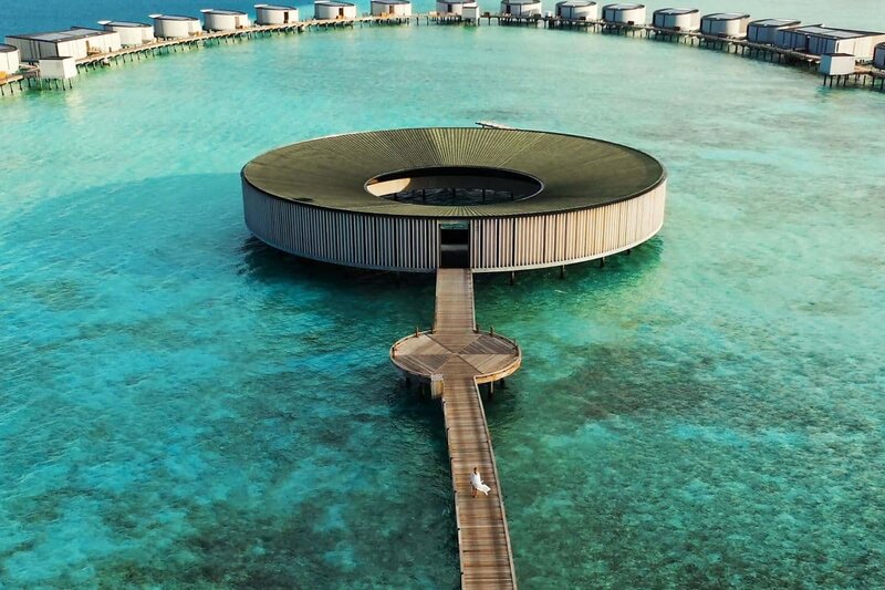 A serene overwater wellness retreat in the Fari Islands, Maldives, featuring a circular spa pavilion surrounded by turquoise waters. Relax and recharge with a bespoke luxury wellness experience, curated by Nadia Forte Travel & Events.